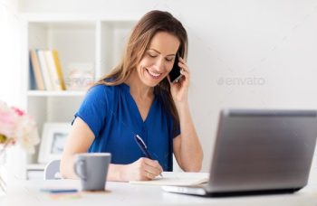 technology, communication and people concept - happy woman calling on smartphone and writing to notebook at office or home
